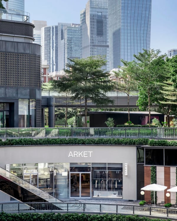 Exterior of an ARKET store with greenery and surrounding city buildings.