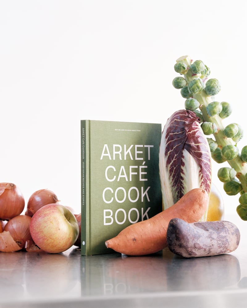 The ARKET Café cookbook propped up among vegetables and fruit.