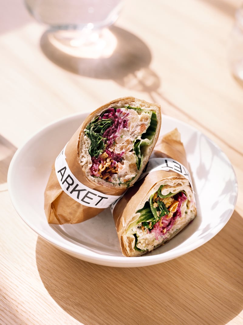 A halved wrap sandwich served on a plate with an ARKET napkin.