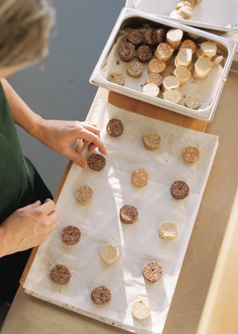 Hands arranging small food items on a lined tray.