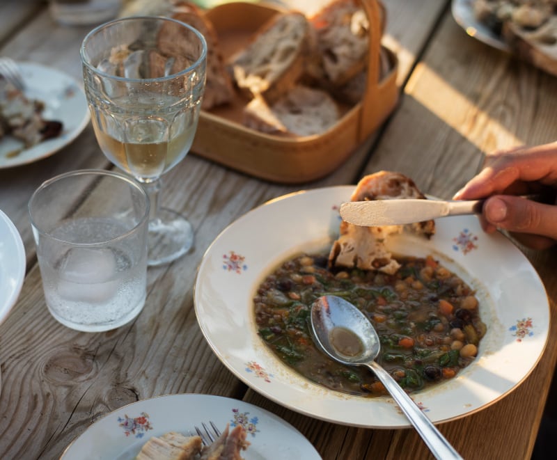 A bowl of stew with bread, served with a spoon.